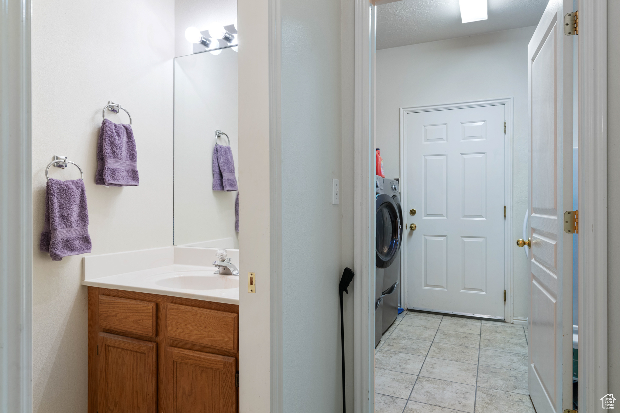 Bathroom featuring washer / clothes dryer, tile patterned flooring, vanity, and a textured ceiling