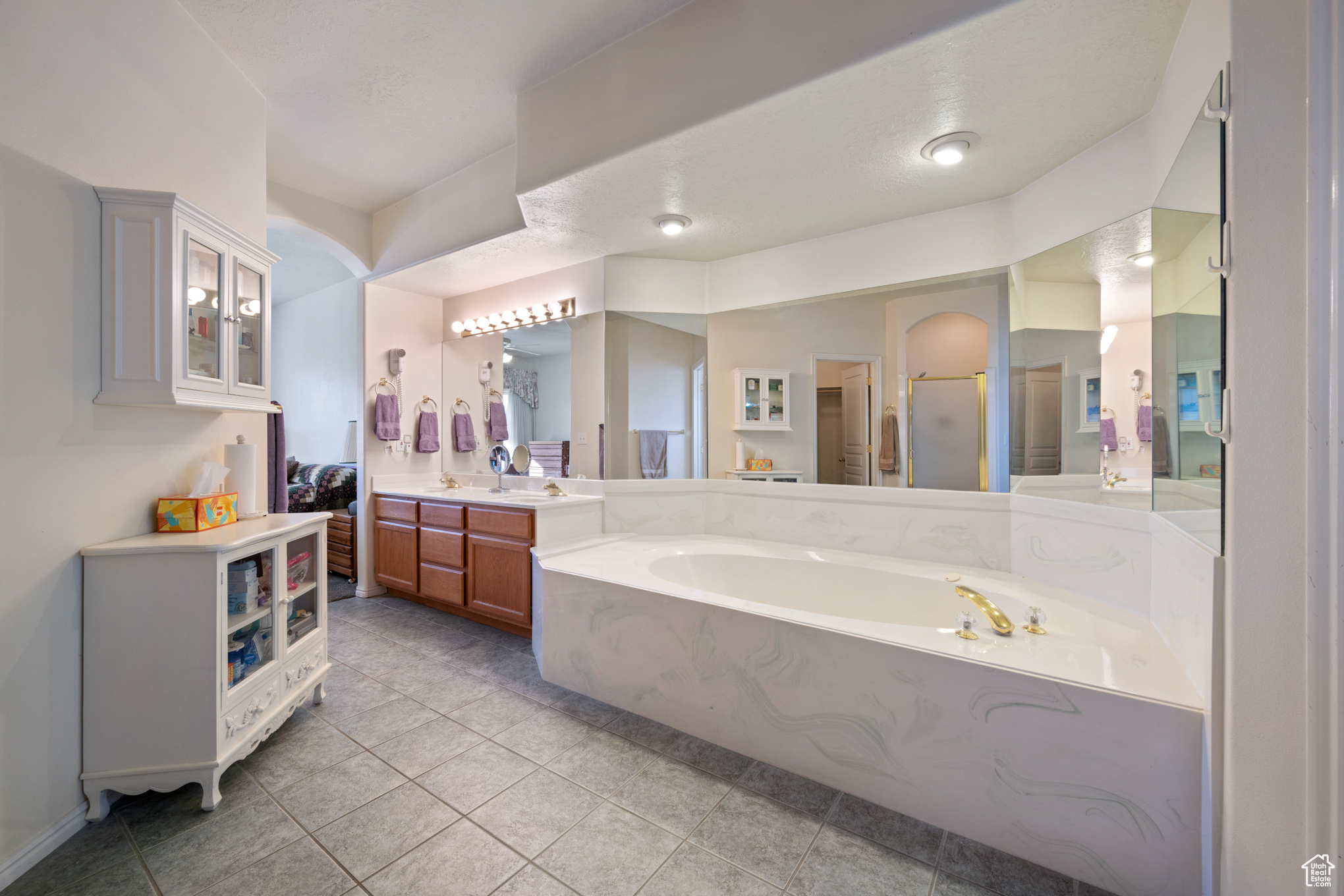 Bathroom featuring tile patterned floors, vanity, and plus walk in shower