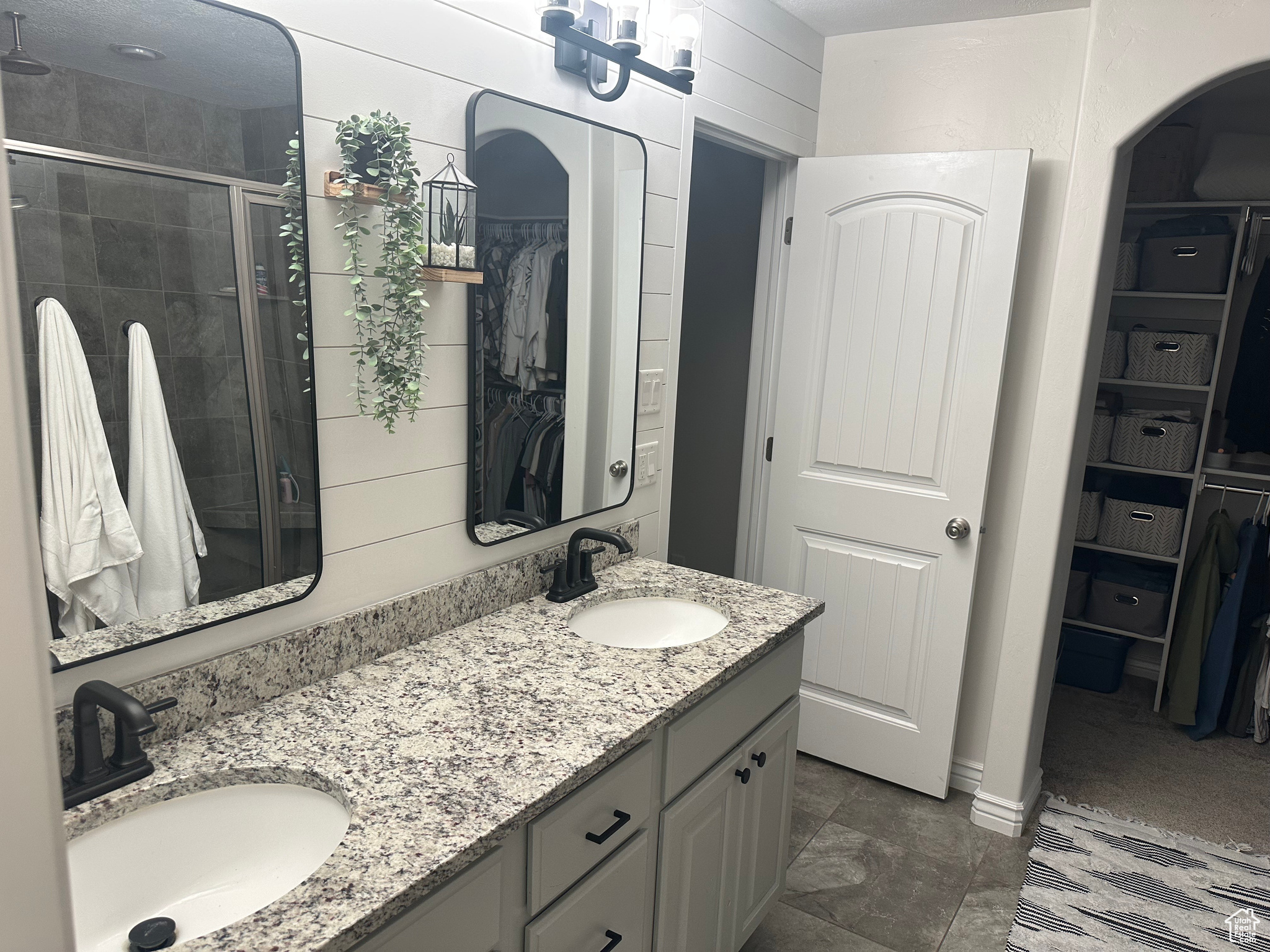 Bathroom featuring wooden walls, vanity, and a shower with shower door