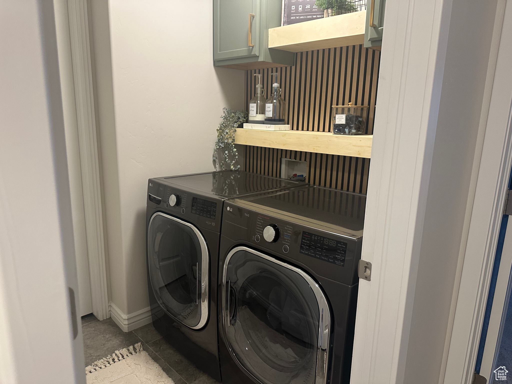 Clothes washing area with separate washer and dryer, light tile patterned floors, and cabinets