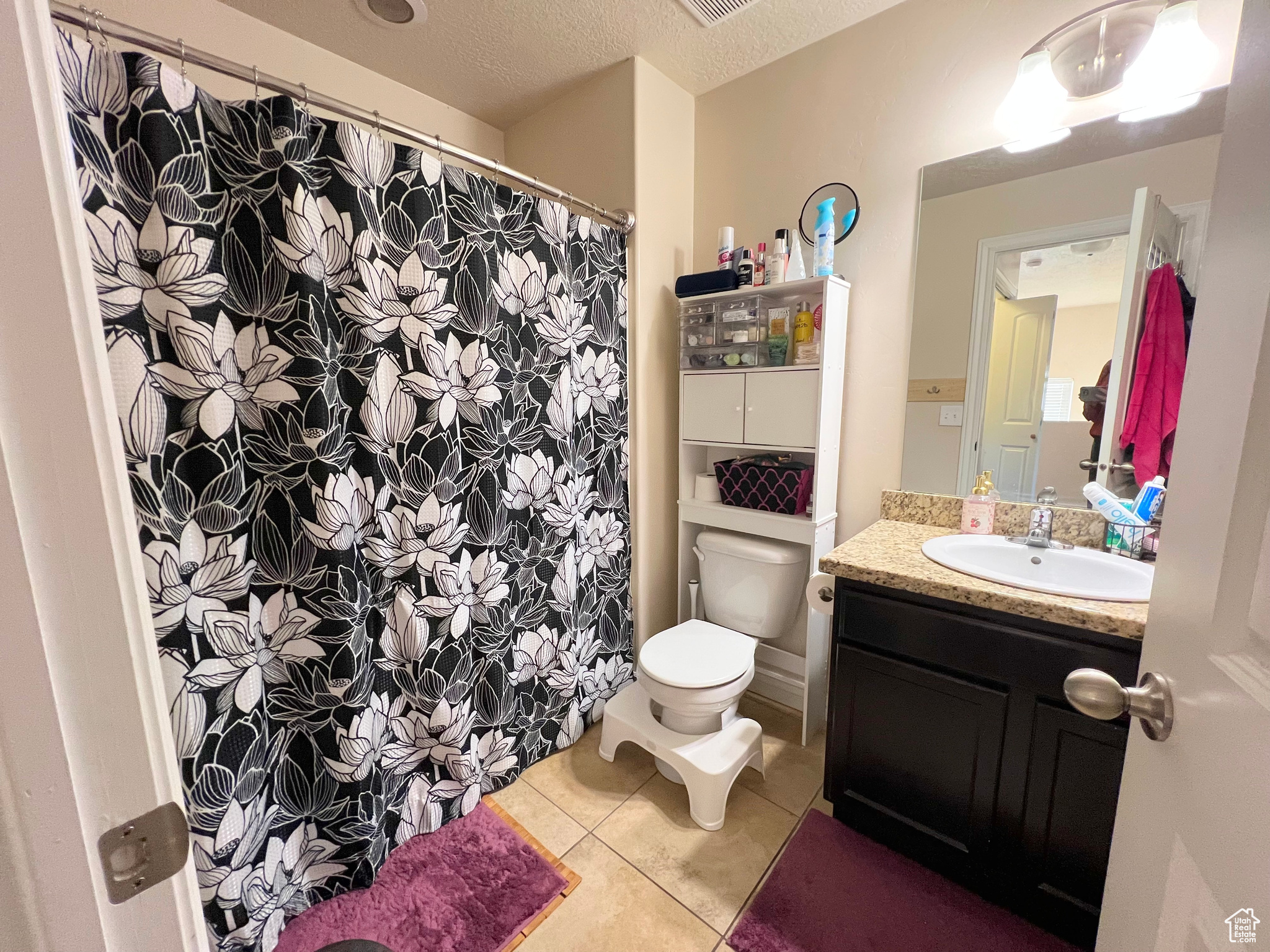 Bathroom featuring tile patterned flooring, vanity, a textured ceiling, and toilet