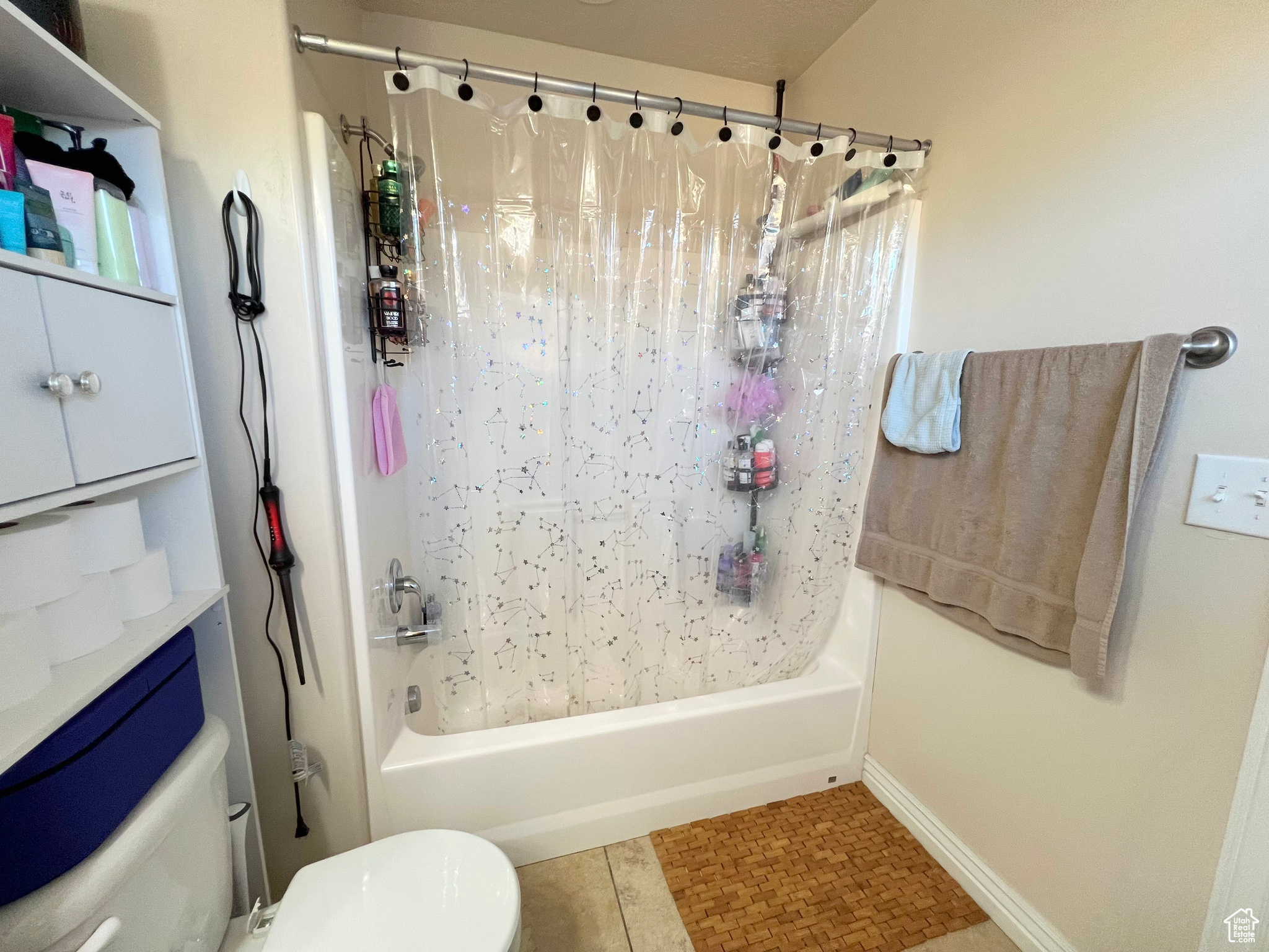 Bathroom featuring tile patterned flooring, shower / bath combination with curtain, and toilet