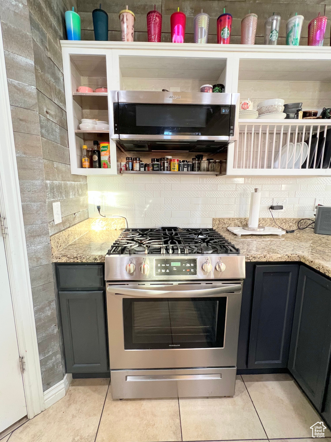 Kitchen with light stone countertops, light tile patterned floors, stainless steel appliances, and decorative backsplash