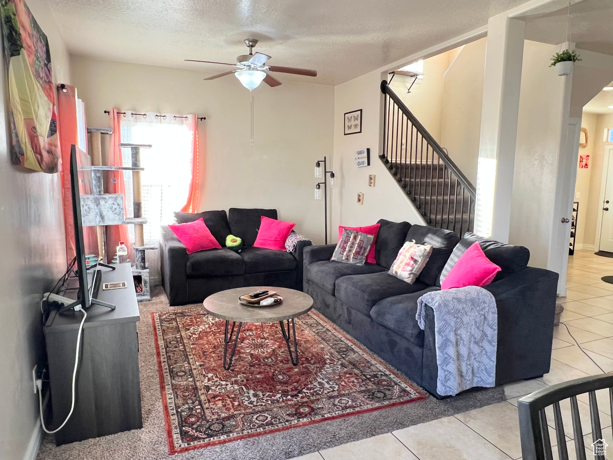 Tiled living room featuring ceiling fan and a textured ceiling