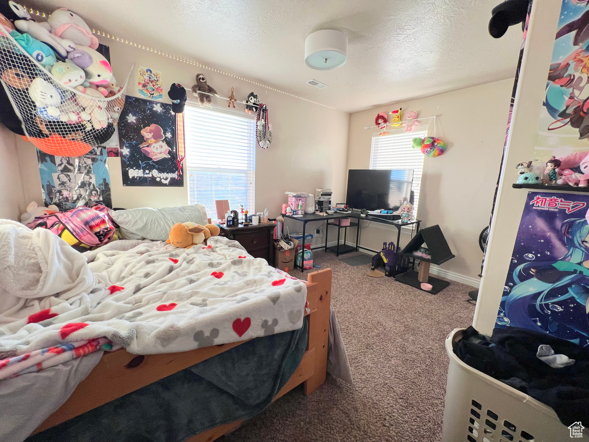 Carpeted bedroom with a textured ceiling and multiple windows