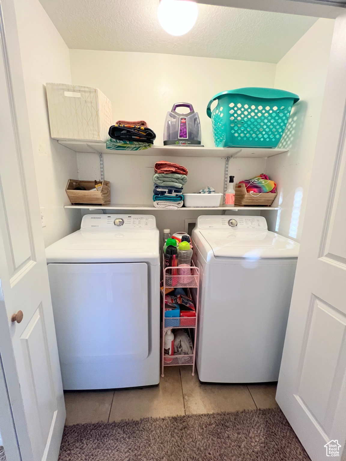 Washroom featuring light tile patterned floors, a textured ceiling, and washer and clothes dryer