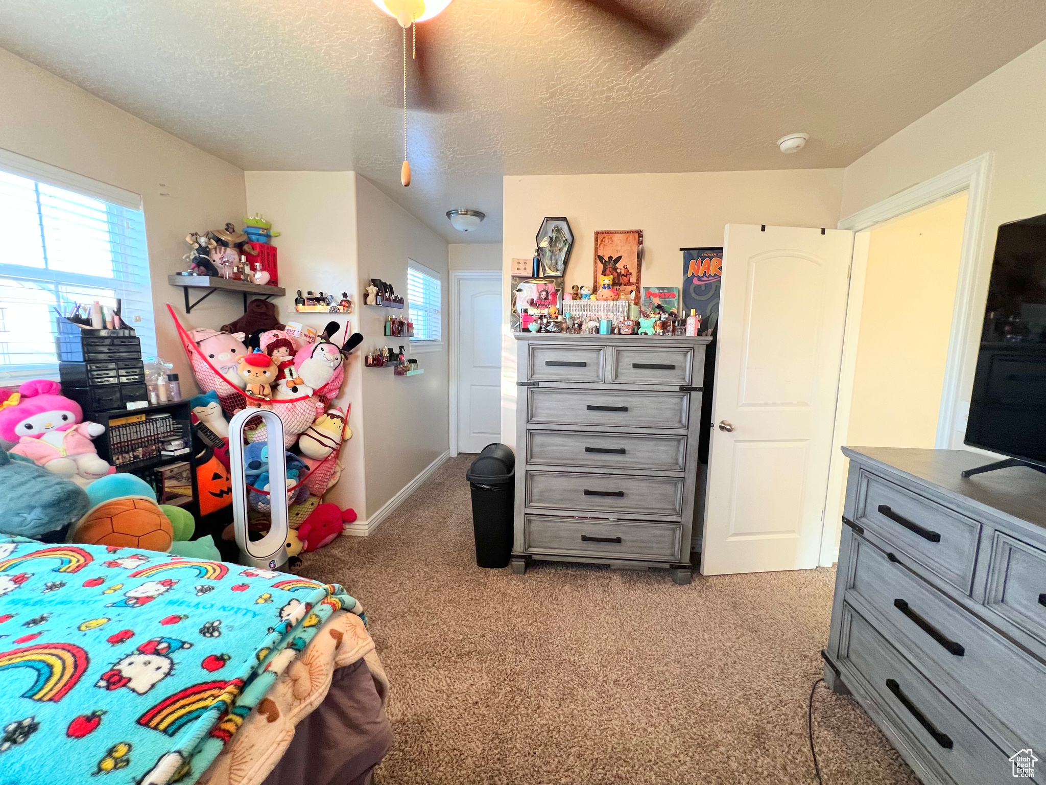 Carpeted bedroom with ceiling fan and a textured ceiling