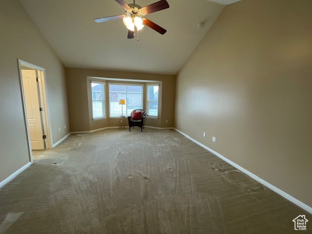 Spare room with ceiling fan, light carpet, and vaulted ceiling