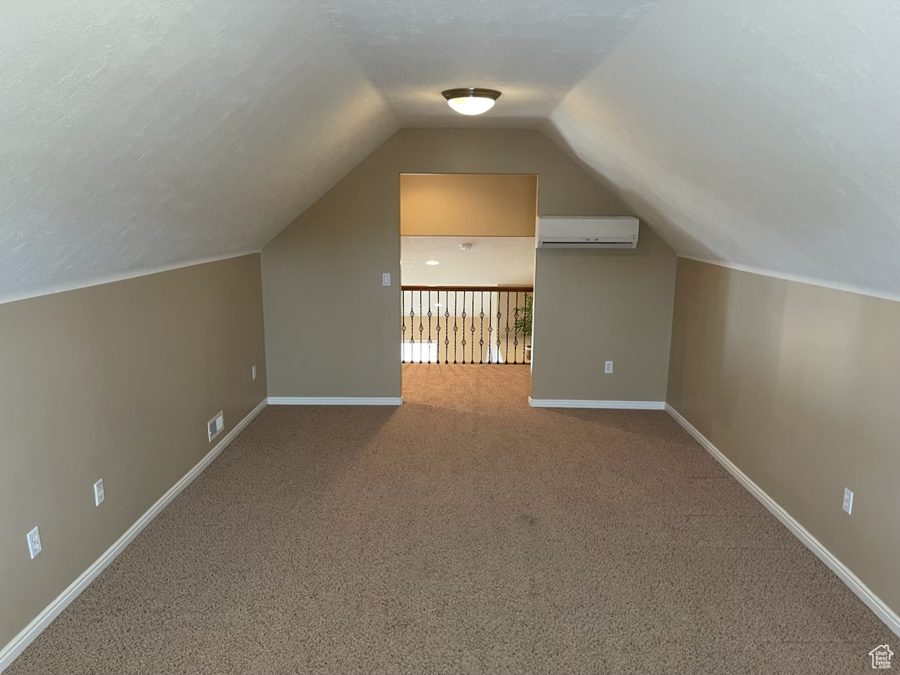 Bonus room with a wall mounted air conditioner, lofted ceiling, carpet floors, and a textured ceiling