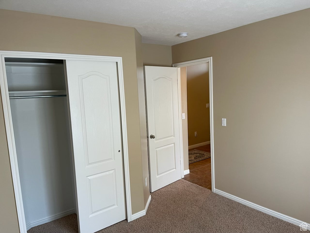 Unfurnished bedroom with a closet and dark carpet