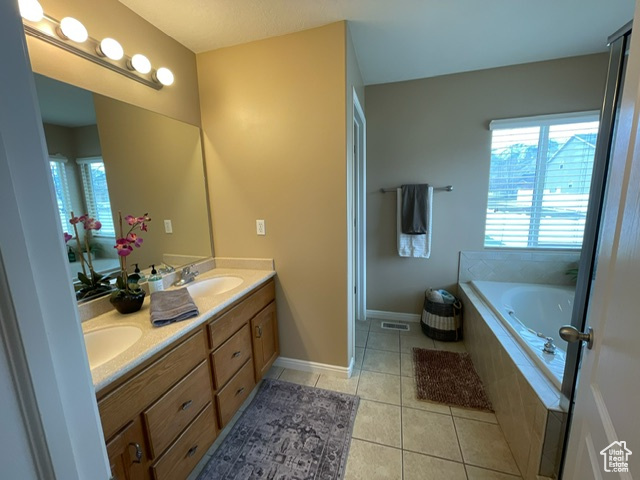 Bathroom featuring tiled bath, tile patterned flooring, and vanity