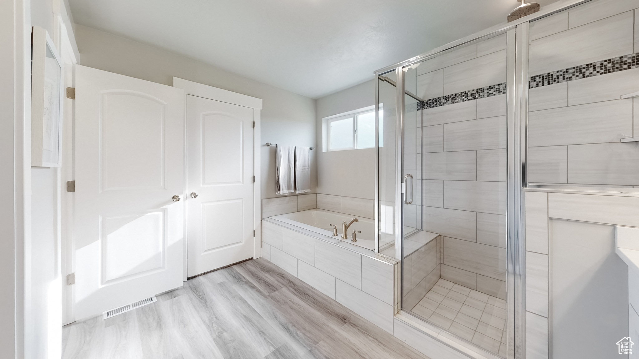 Bathroom with hardwood / wood-style flooring and shower with separate bathtub