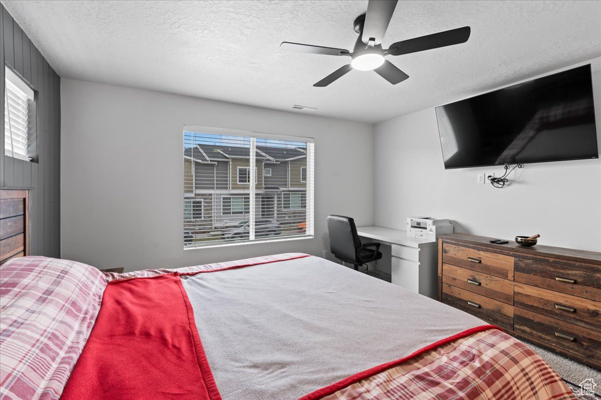 Bedroom with ceiling fan and a textured ceiling