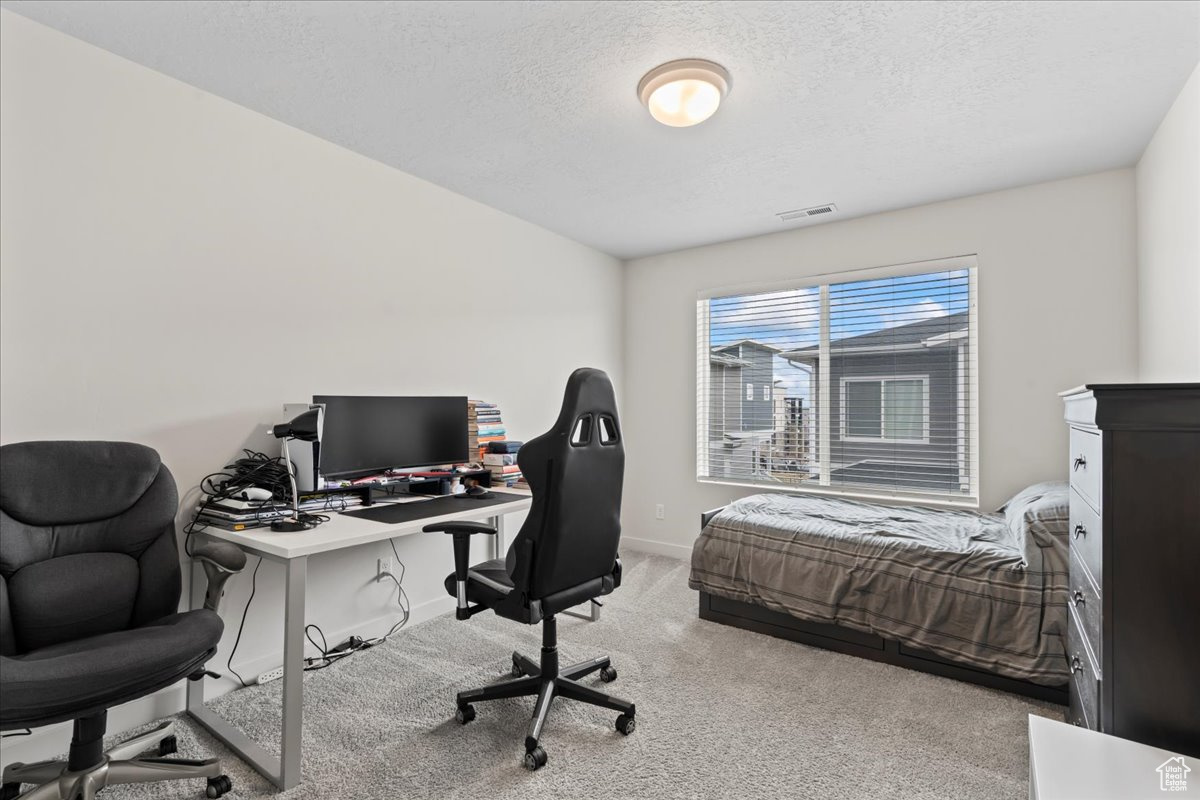 Bedroom featuring light colored carpet and a textured ceiling