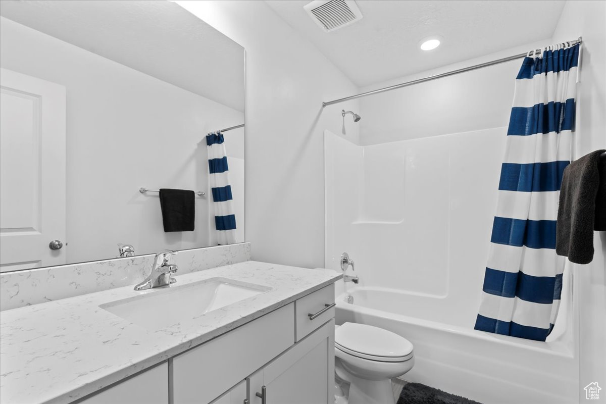 Full bathroom with toilet, vanity, and shower / tub combo with curtain