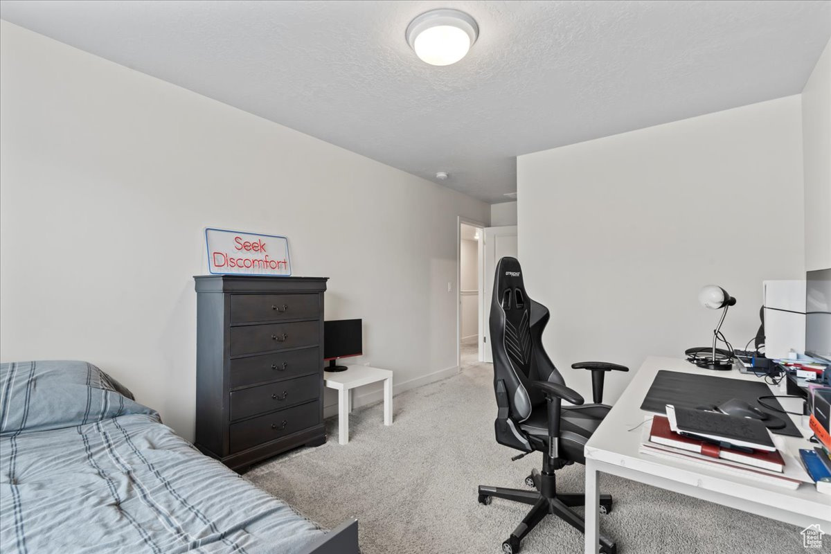 Home office featuring a textured ceiling and light carpet