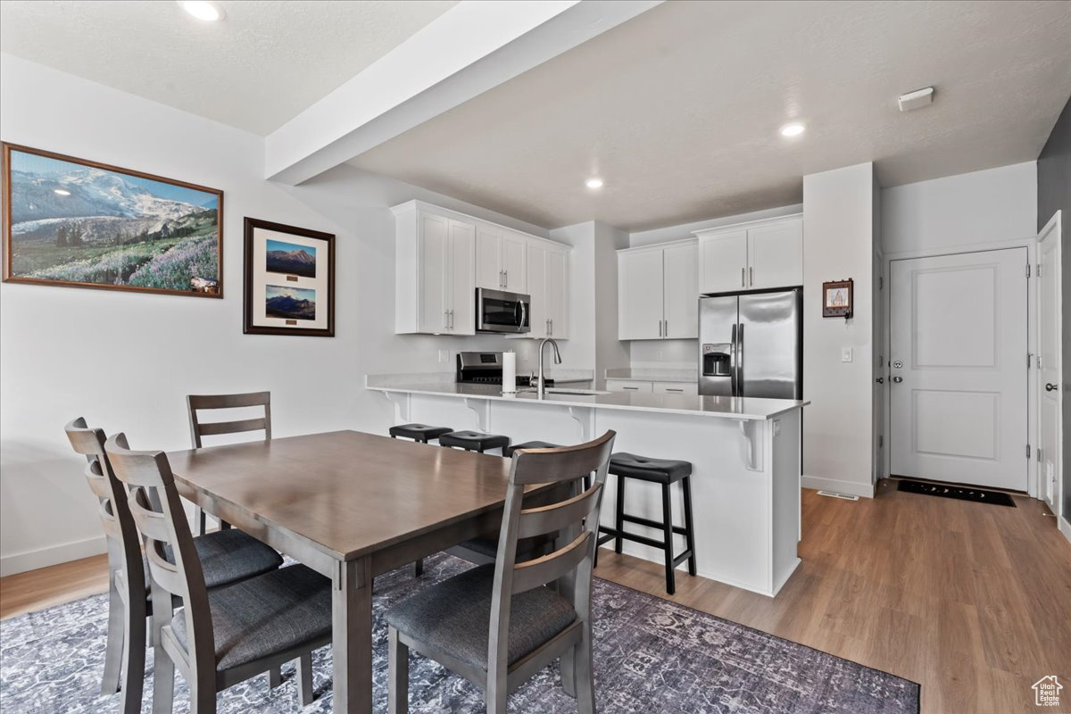 Dining space with sink, beamed ceiling, and light hardwood / wood-style floors