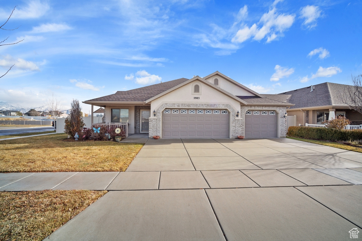 Ranch-style house featuring a front yard, a porch, and a garage