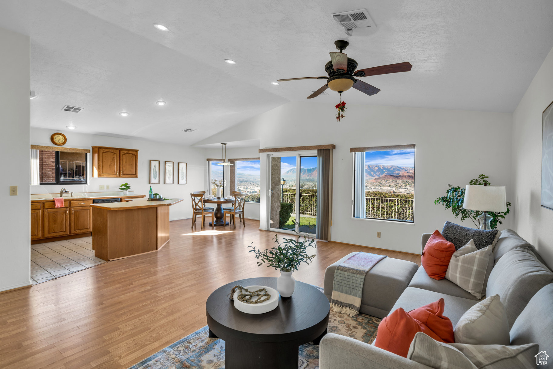 Living room featuring ceiling fan, light hardwood / wood-style floors, sink, and vaulted ceiling