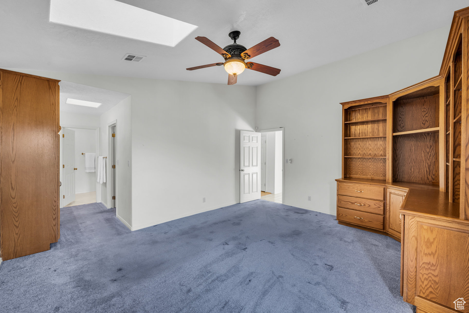 Interior space featuring carpet, ceiling fan, and a skylight