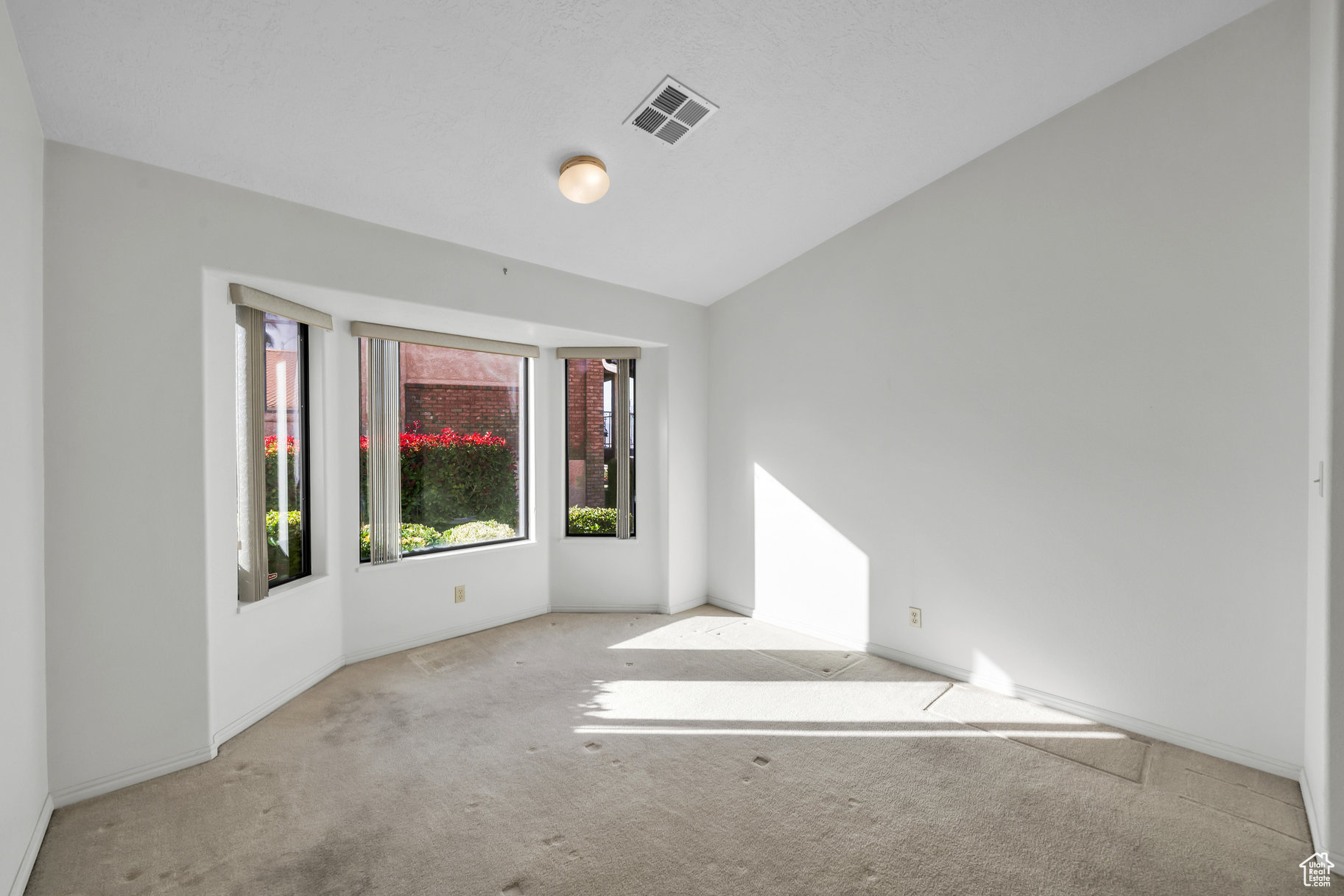 Carpeted spare room with vaulted ceiling