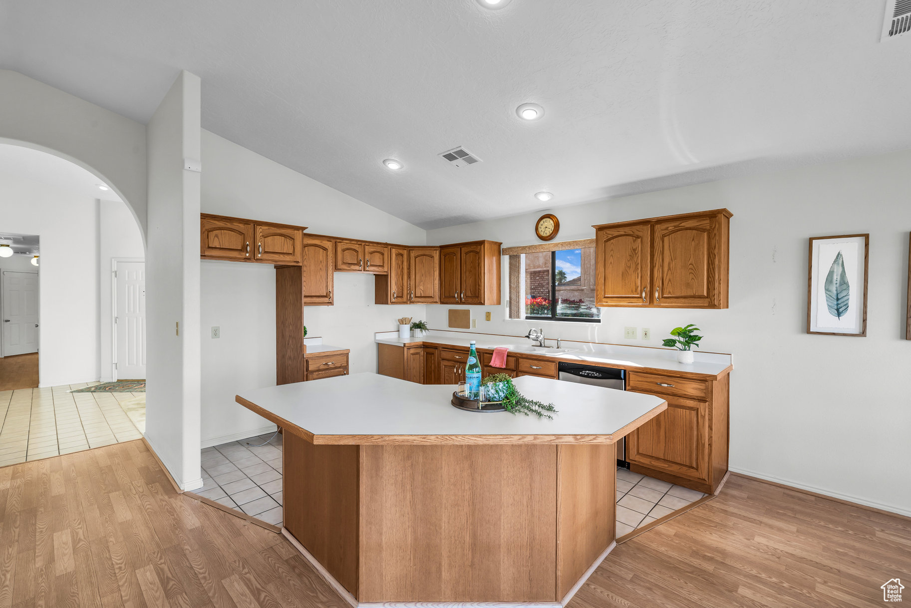 Kitchen with dishwasher, a center island, light hardwood / wood-style floors, and lofted ceiling