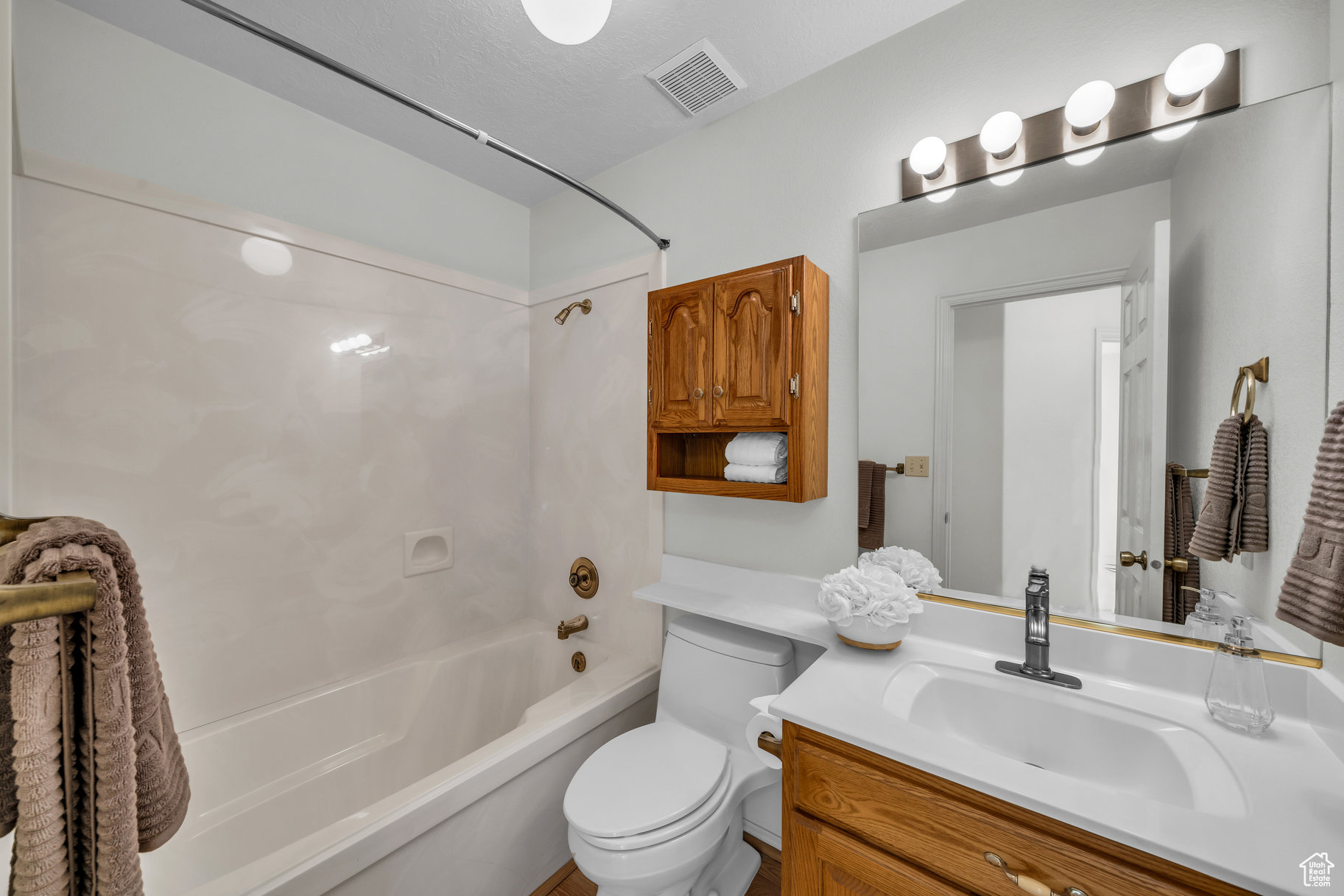 Full bathroom featuring toilet, vanity, a textured ceiling, and washtub / shower combination