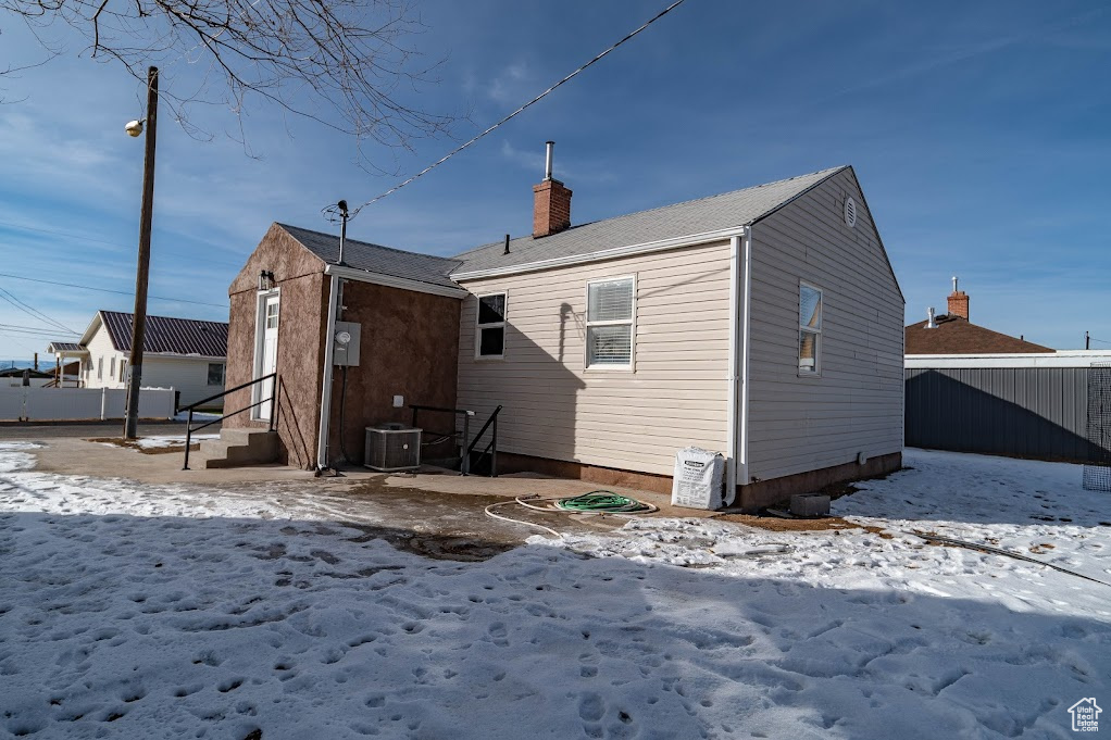 Snow covered rear of property featuring central AC