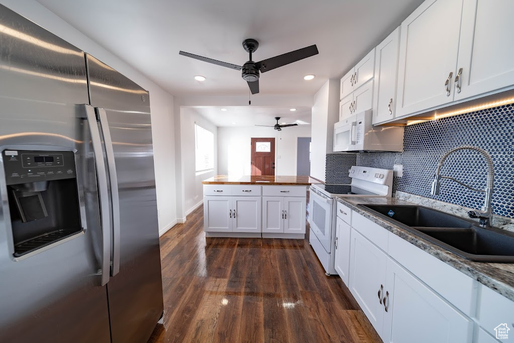 Kitchen featuring white appliances, sink, decorative backsplash, ceiling fan, and white cabinetry