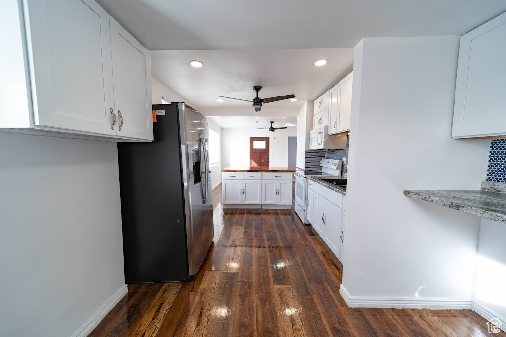 Kitchen featuring white cabinets, dark hardwood / wood-style floors, decorative backsplash, and white appliances