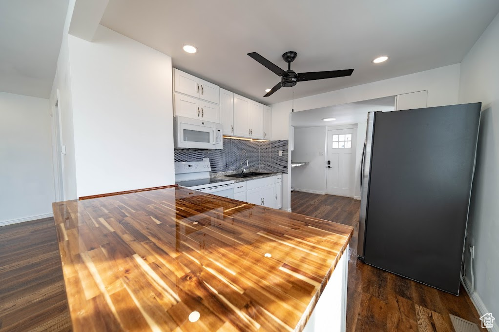 Kitchen with wood counters, stove, white cabinetry, and stainless steel refrigerator