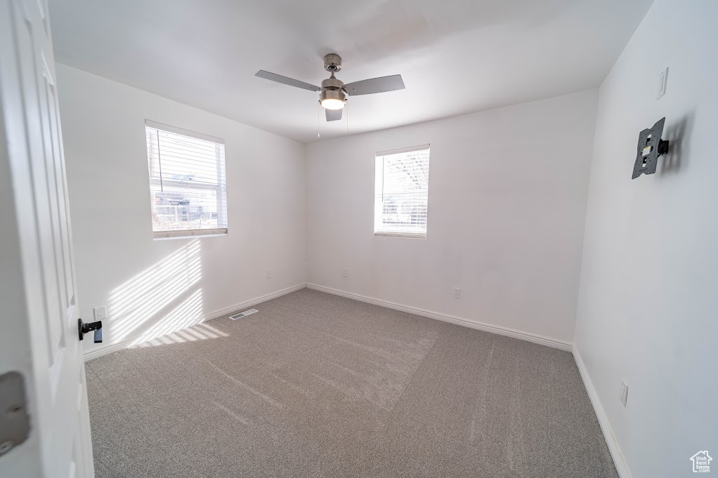 Spare room with plenty of natural light, ceiling fan, and carpet floors