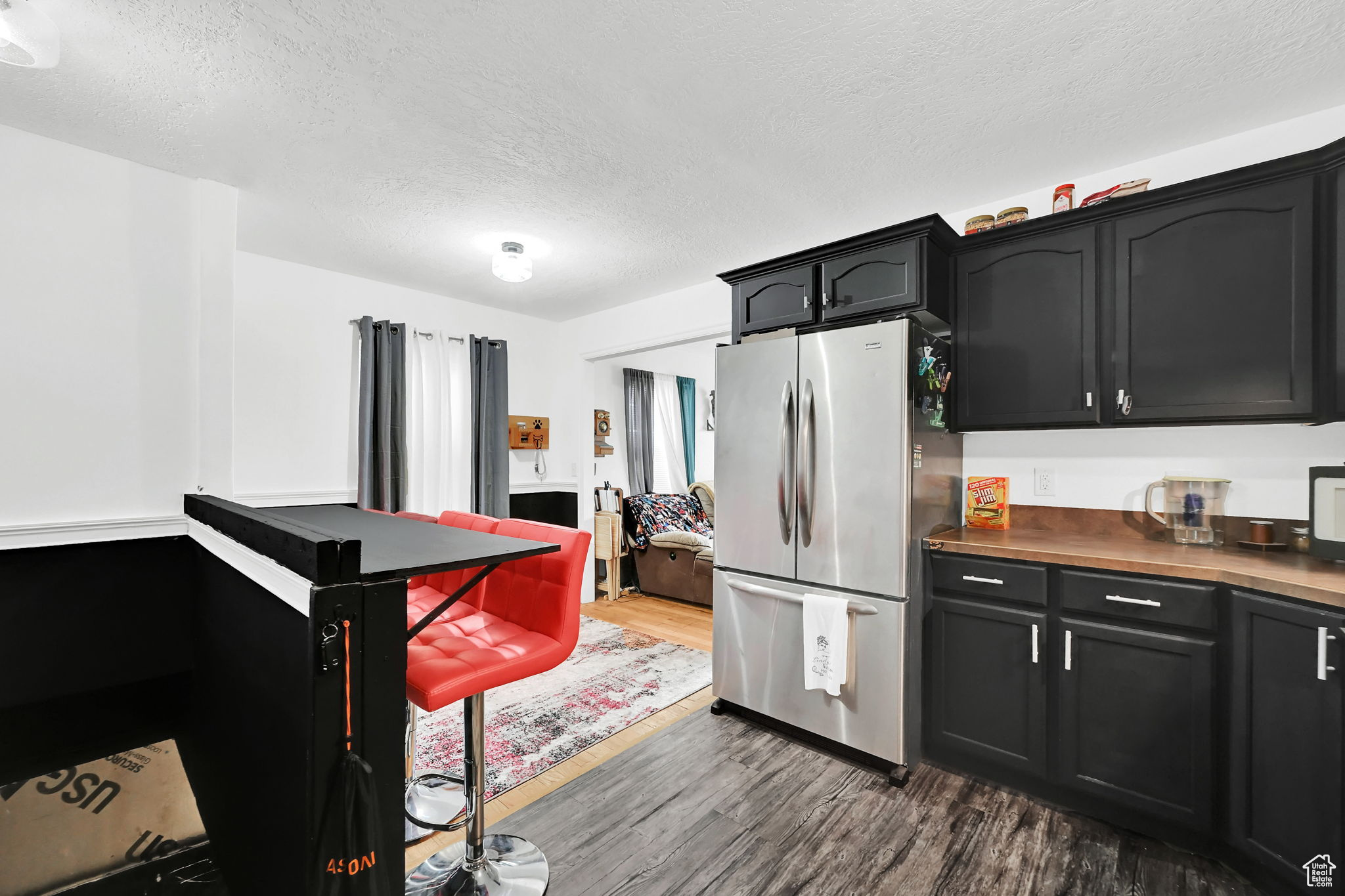 Kitchen featuring stainless steel fridge, dark hardwood / wood-style flooring, and a textured ceiling