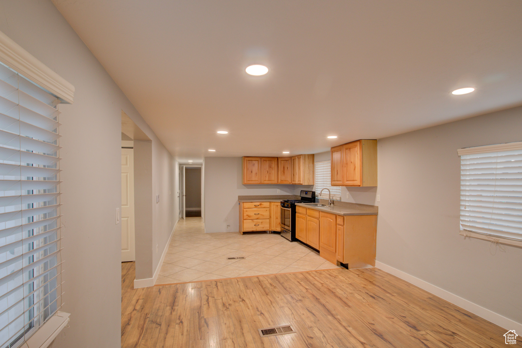 Kitchen featuring light hardwood / wood-style floors, black range with gas stovetop, sink, and light brown cabinetry