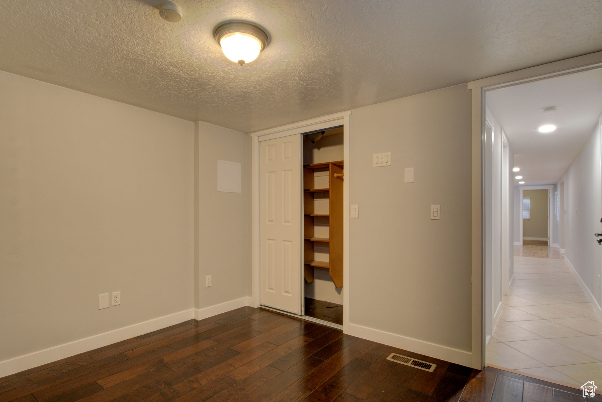 Empty room featuring a textured ceiling and dark wood-type flooring