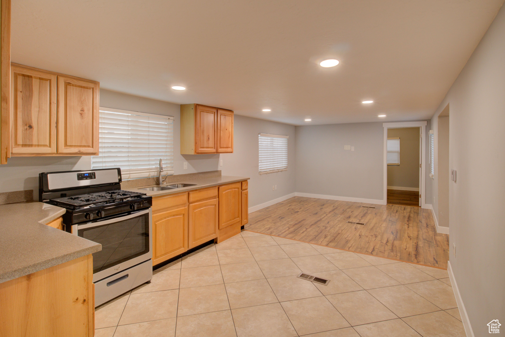 Kitchen featuring light tile patterned flooring, sink, light brown cabinetry, and stainless steel gas range