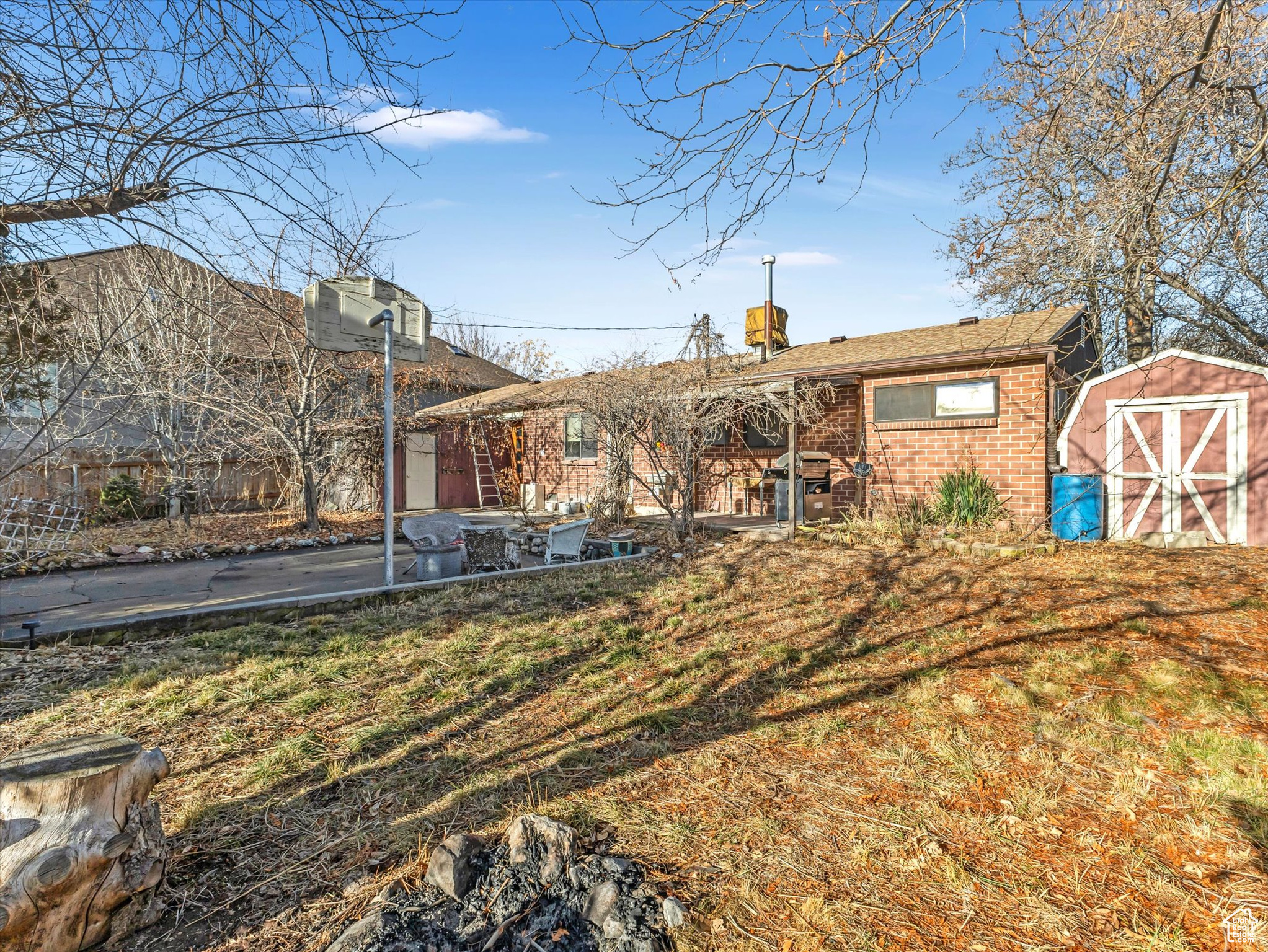 Back of house with a lawn, a patio, and a shed