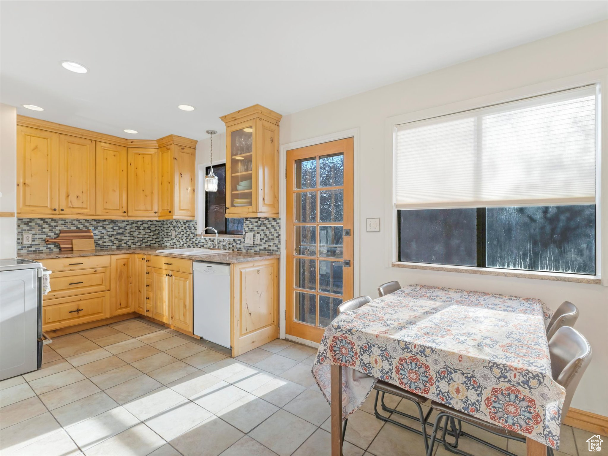 Kitchen featuring dishwasher, light brown cabinets, backsplash, stove, and light tile patterned floors