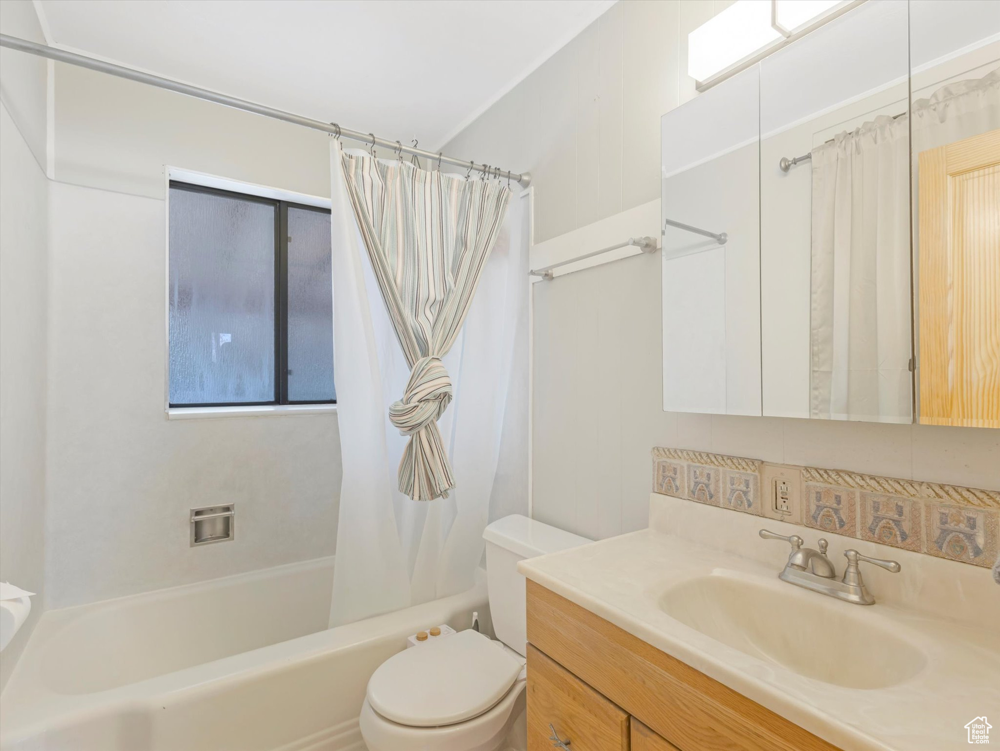 Full bathroom with vanity, toilet, and shower / bath combo with shower curtain