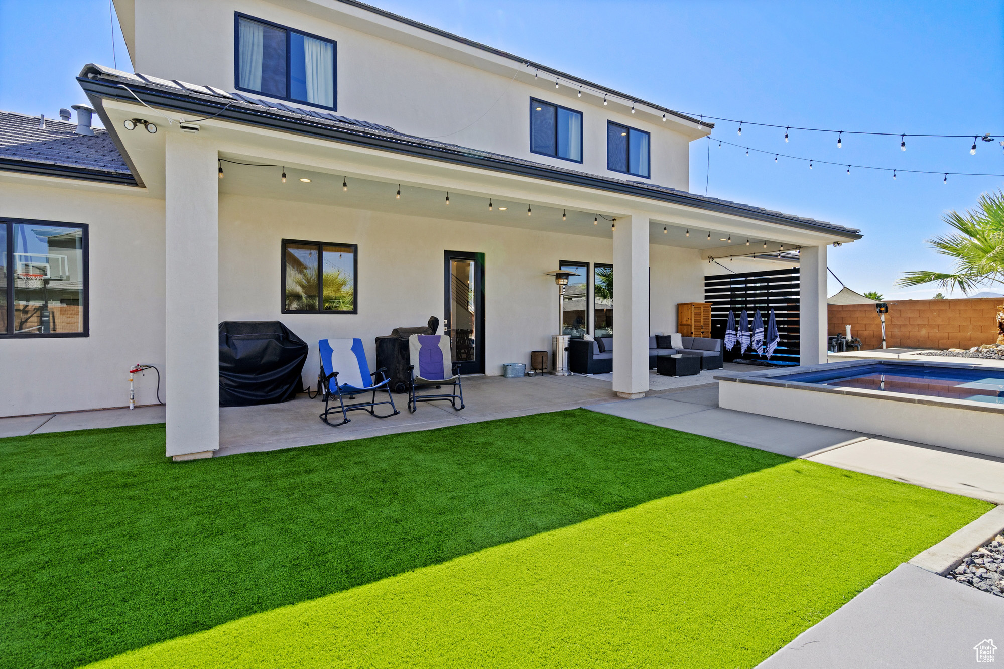 Rear view of house featuring an outdoor living space, a pool, a patio area, and a lawn