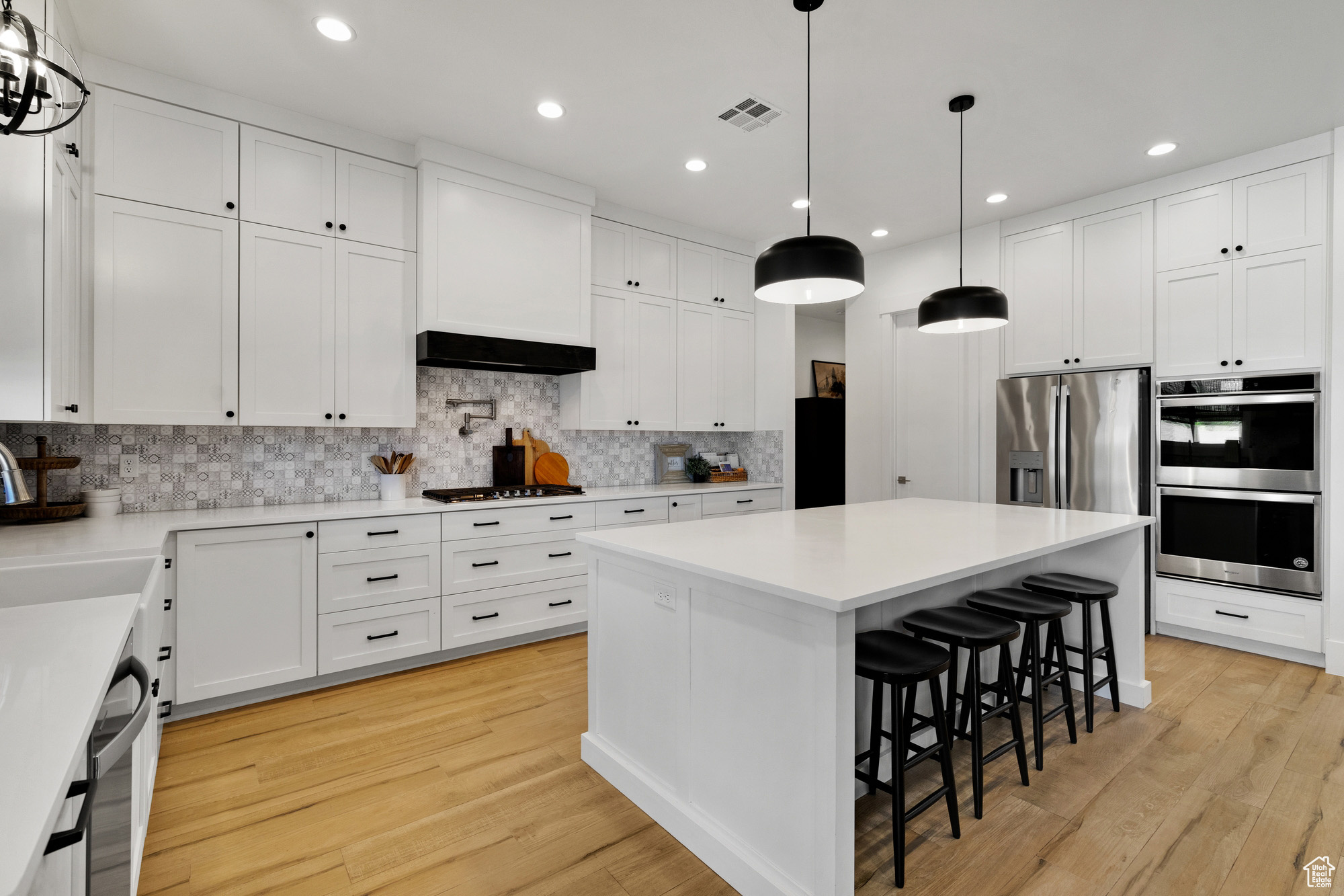 Kitchen featuring white cabinetry, a kitchen island, decorative light fixtures, and light wood-type flooring