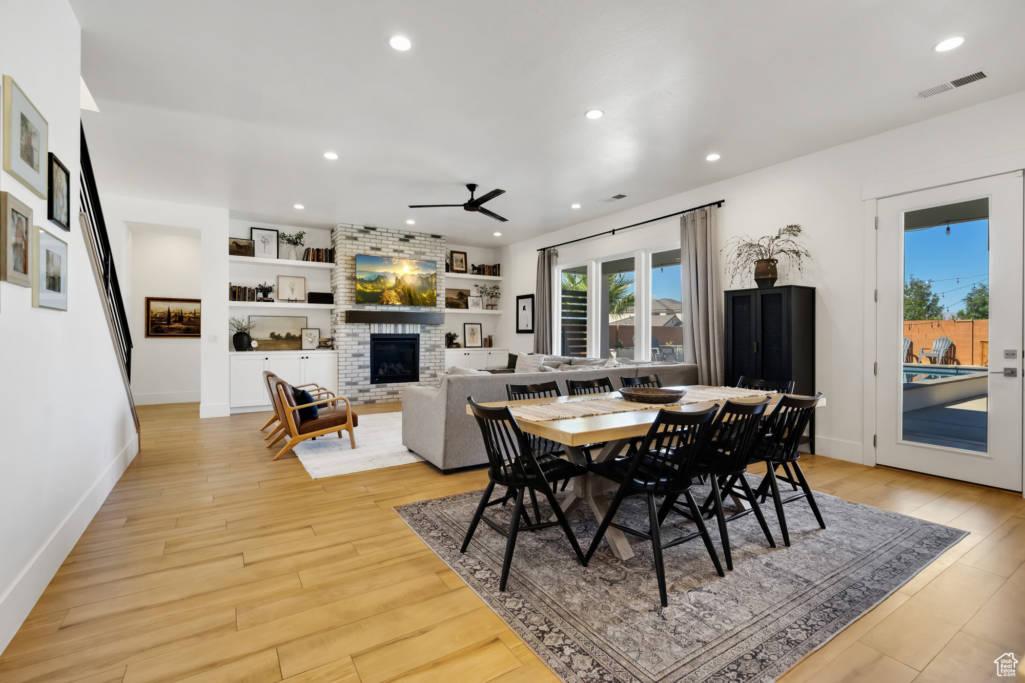 Dining room with built in shelves, ceiling fan, light hardwood / wood-style floors, and a fireplace