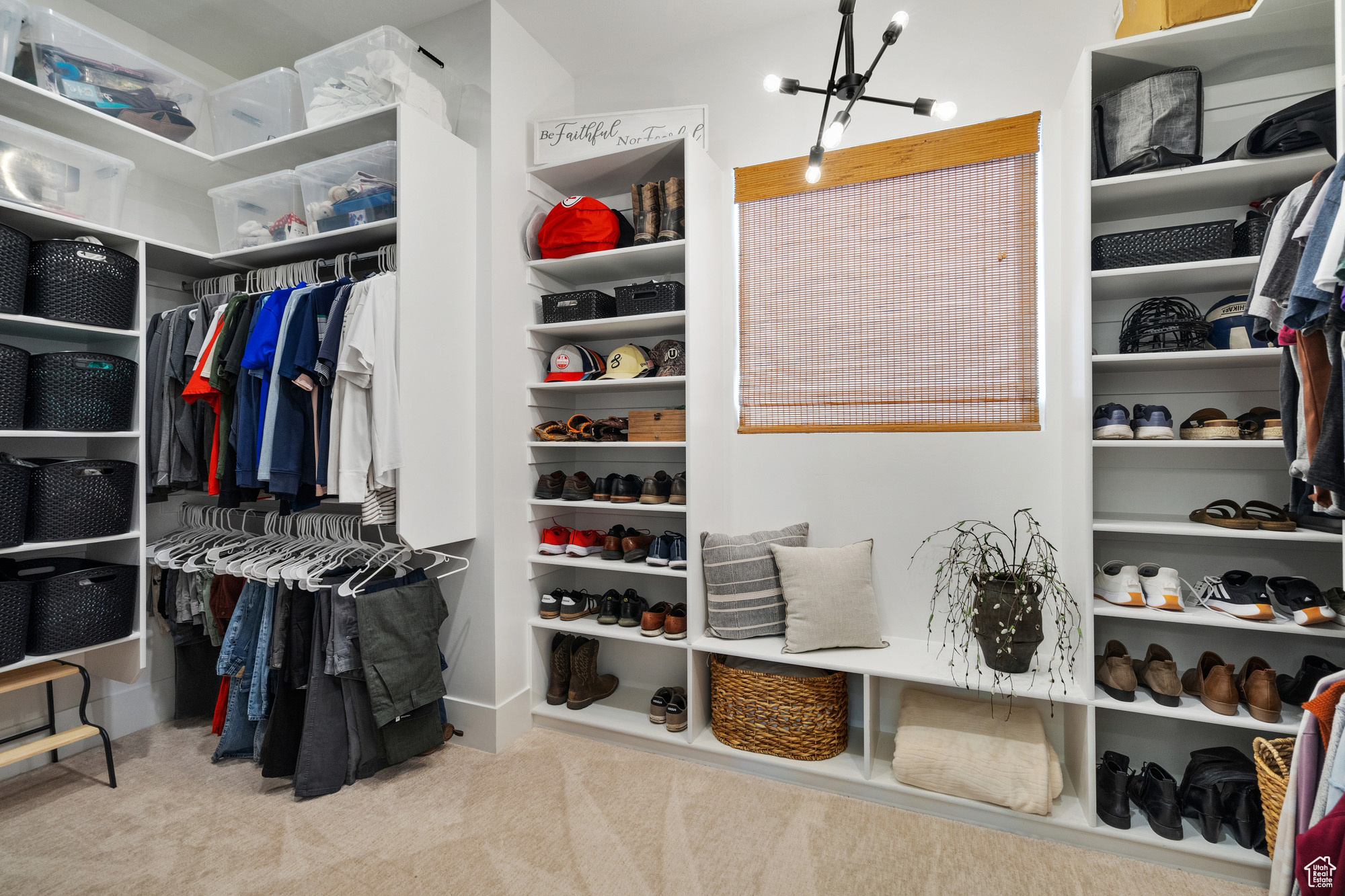 Walk in closet with light carpet and a chandelier