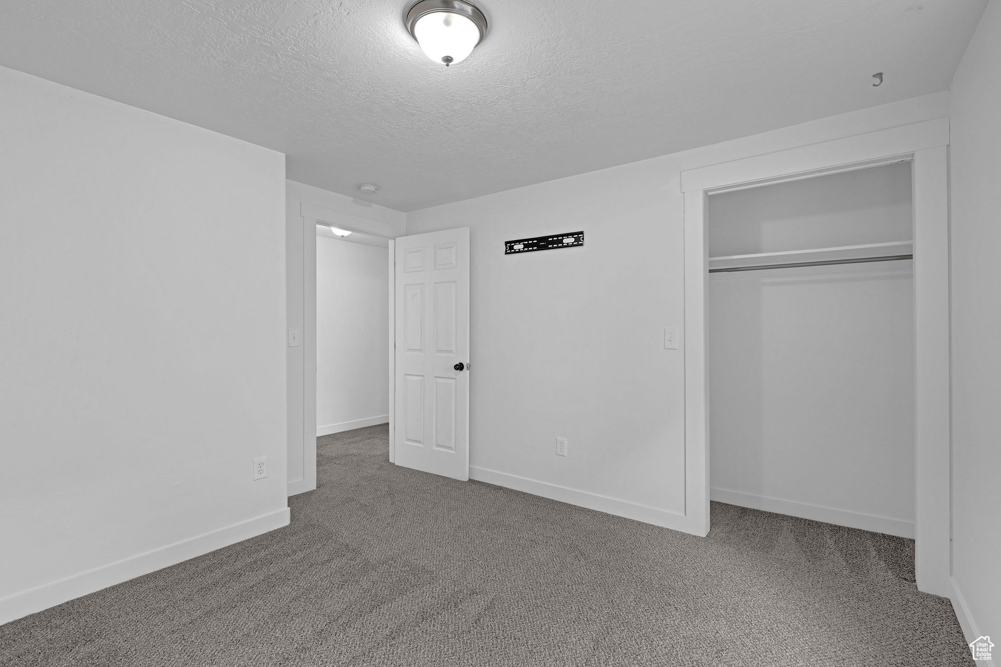 Unfurnished bedroom featuring carpet, a textured ceiling, and a closet