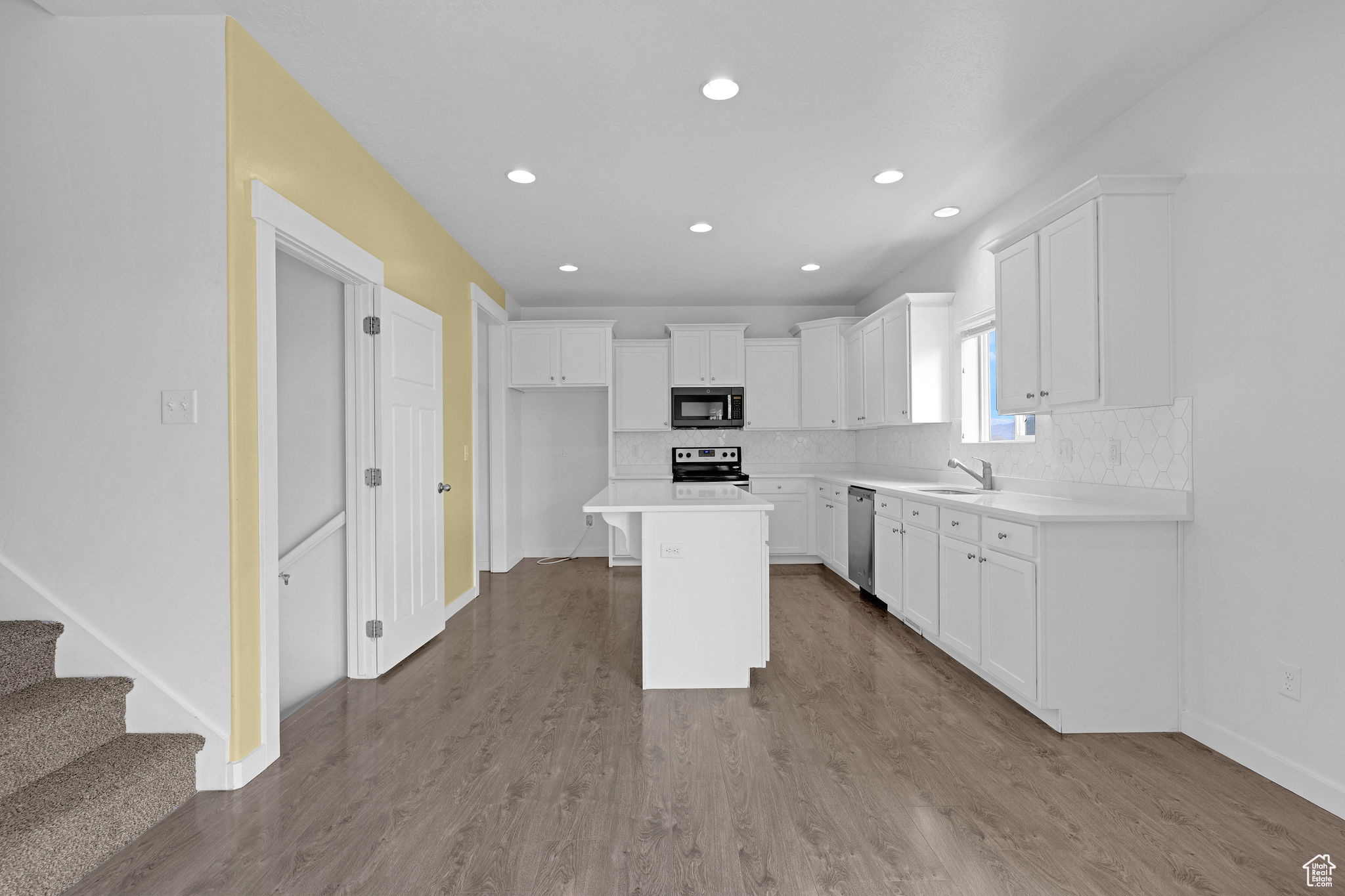 Kitchen featuring a center island, white cabinets, light wood-type flooring, tasteful backsplash, and stainless steel appliances