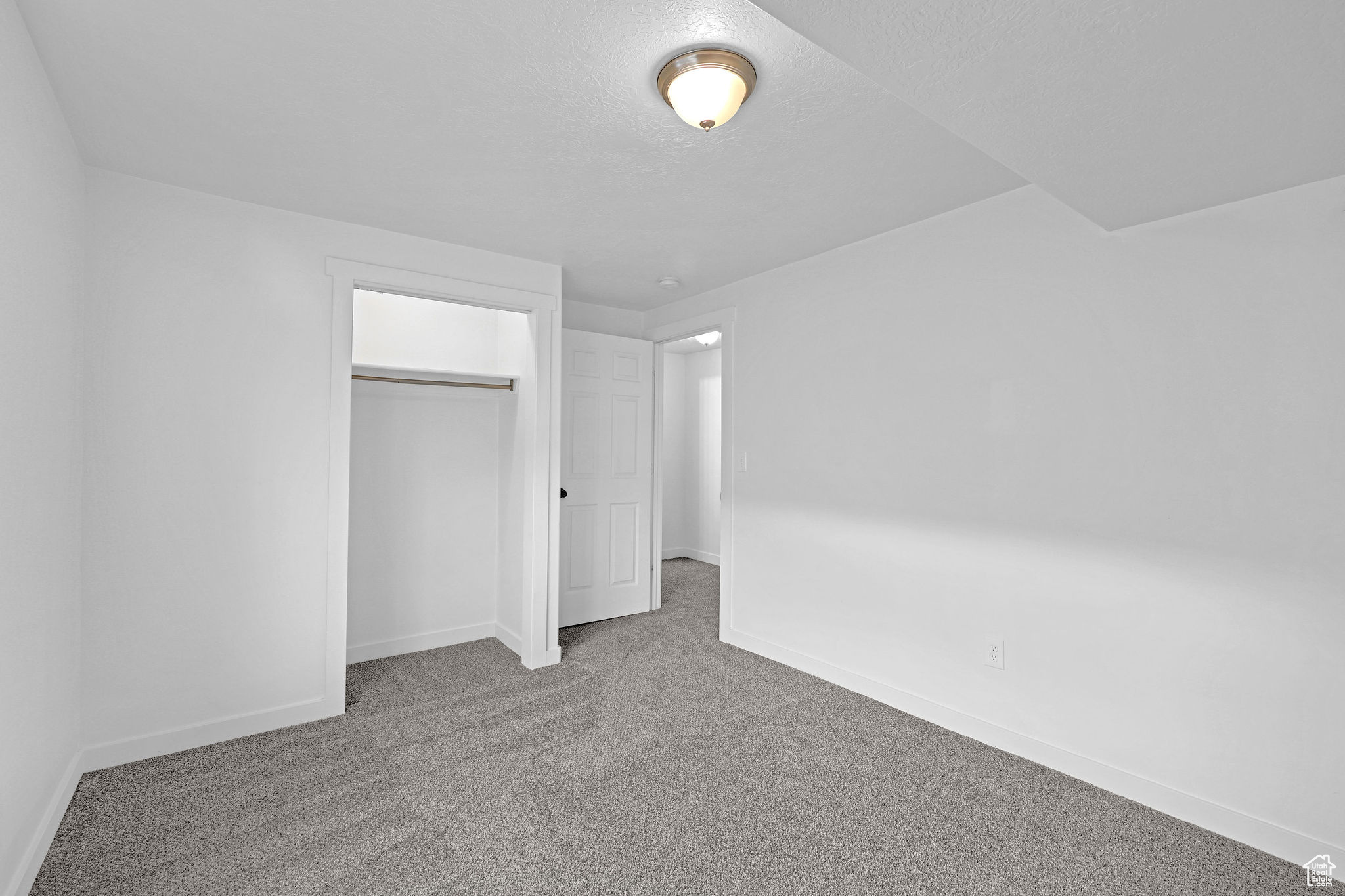 Unfurnished bedroom with carpet flooring, a textured ceiling, and a closet