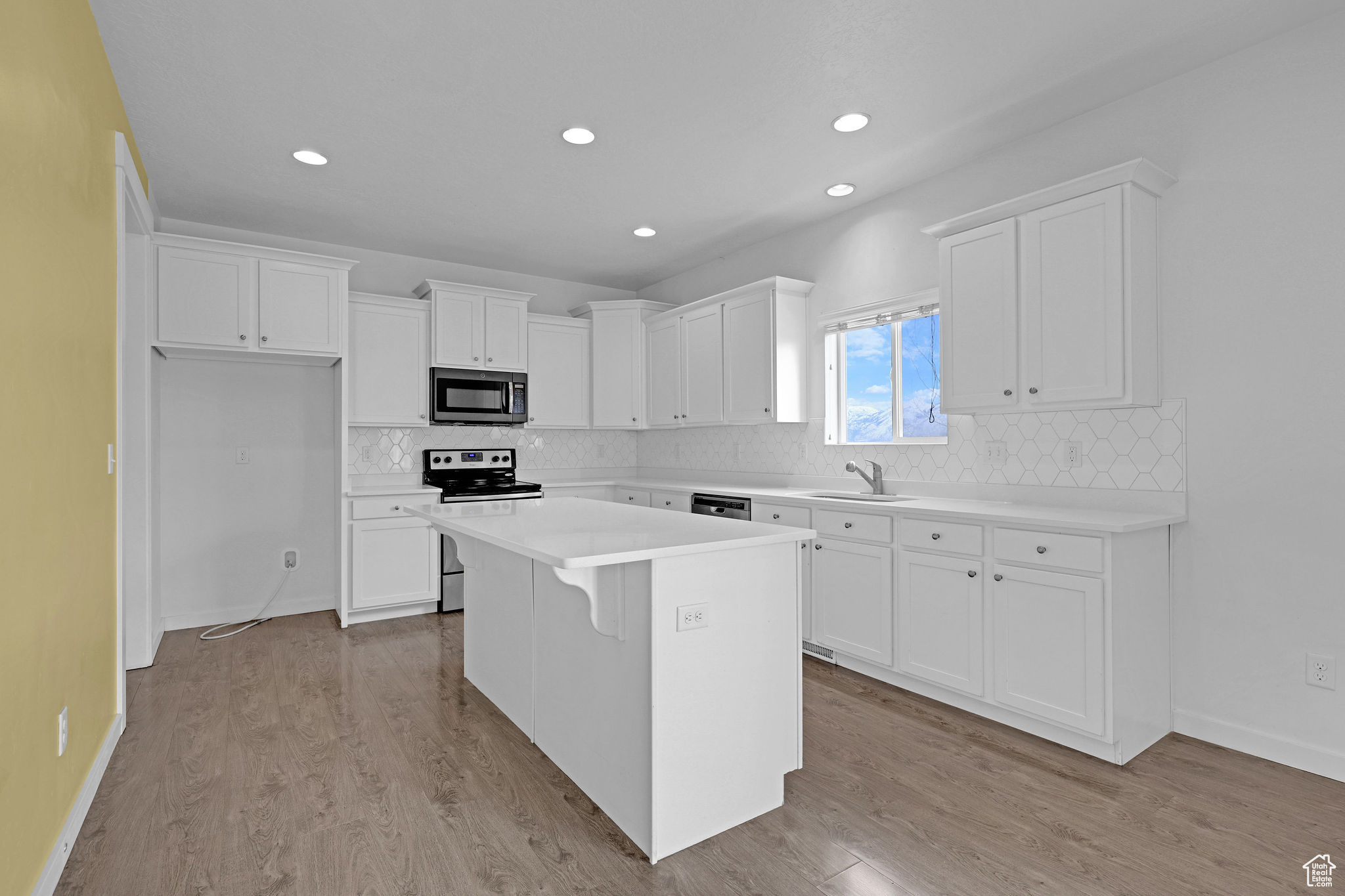 Kitchen with white cabinets, appliances with stainless steel finishes, a center island, and sink