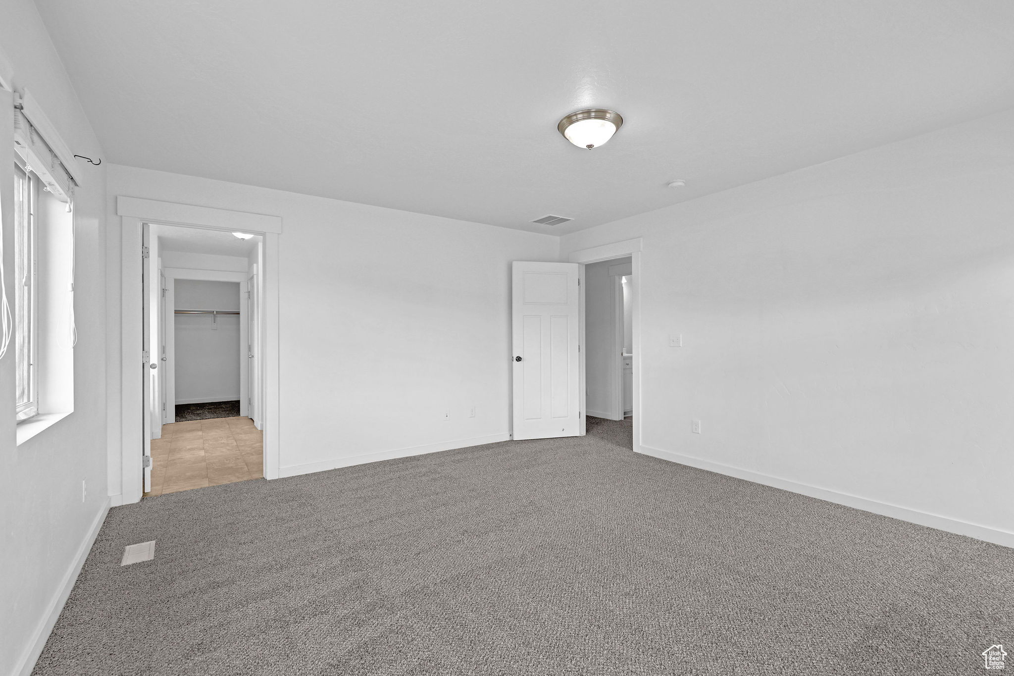 Unfurnished bedroom featuring a spacious closet, light carpet, and a closet