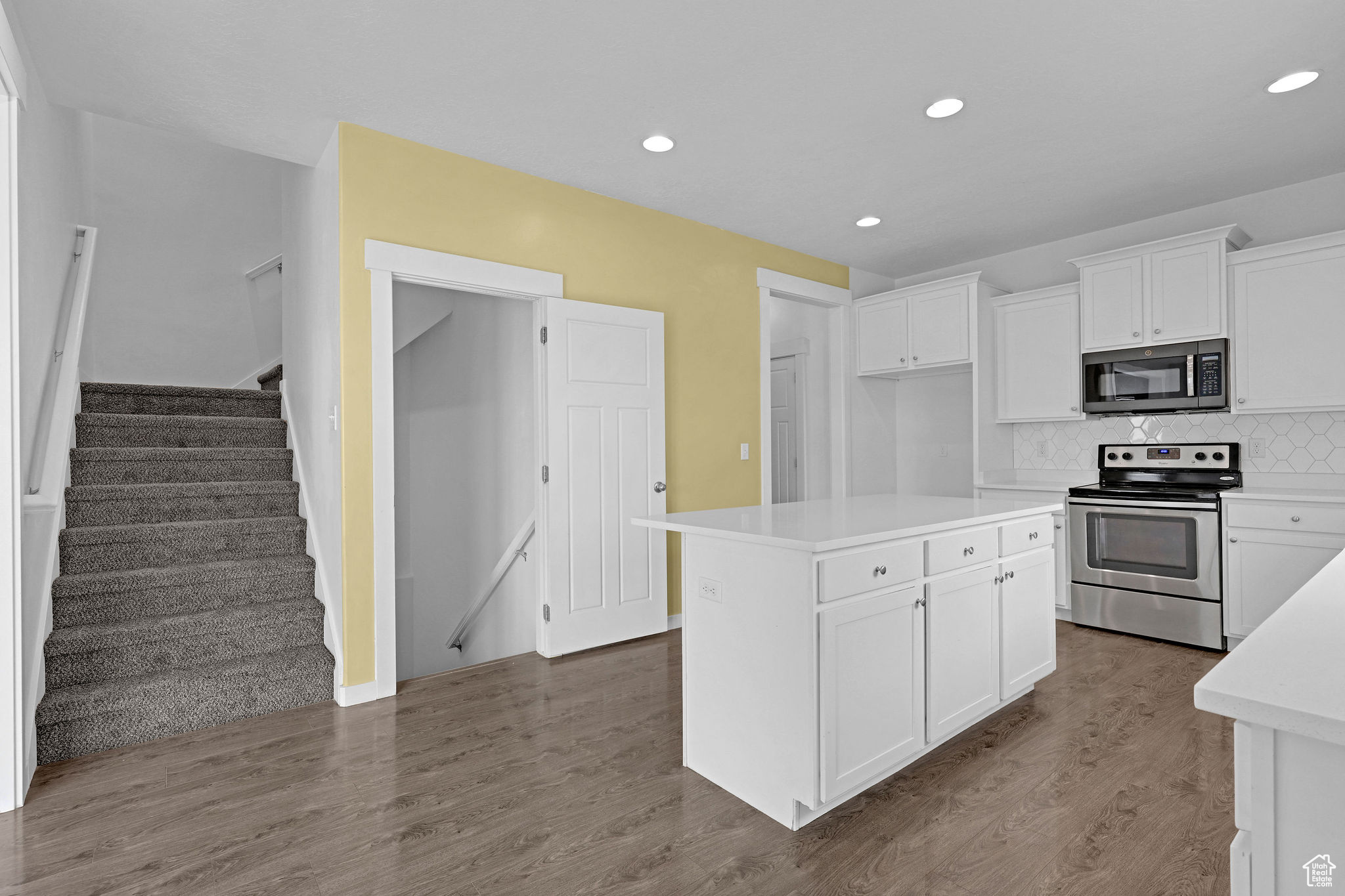 Kitchen featuring stainless steel electric stove, a center island, white cabinets, and hardwood / wood-style floors