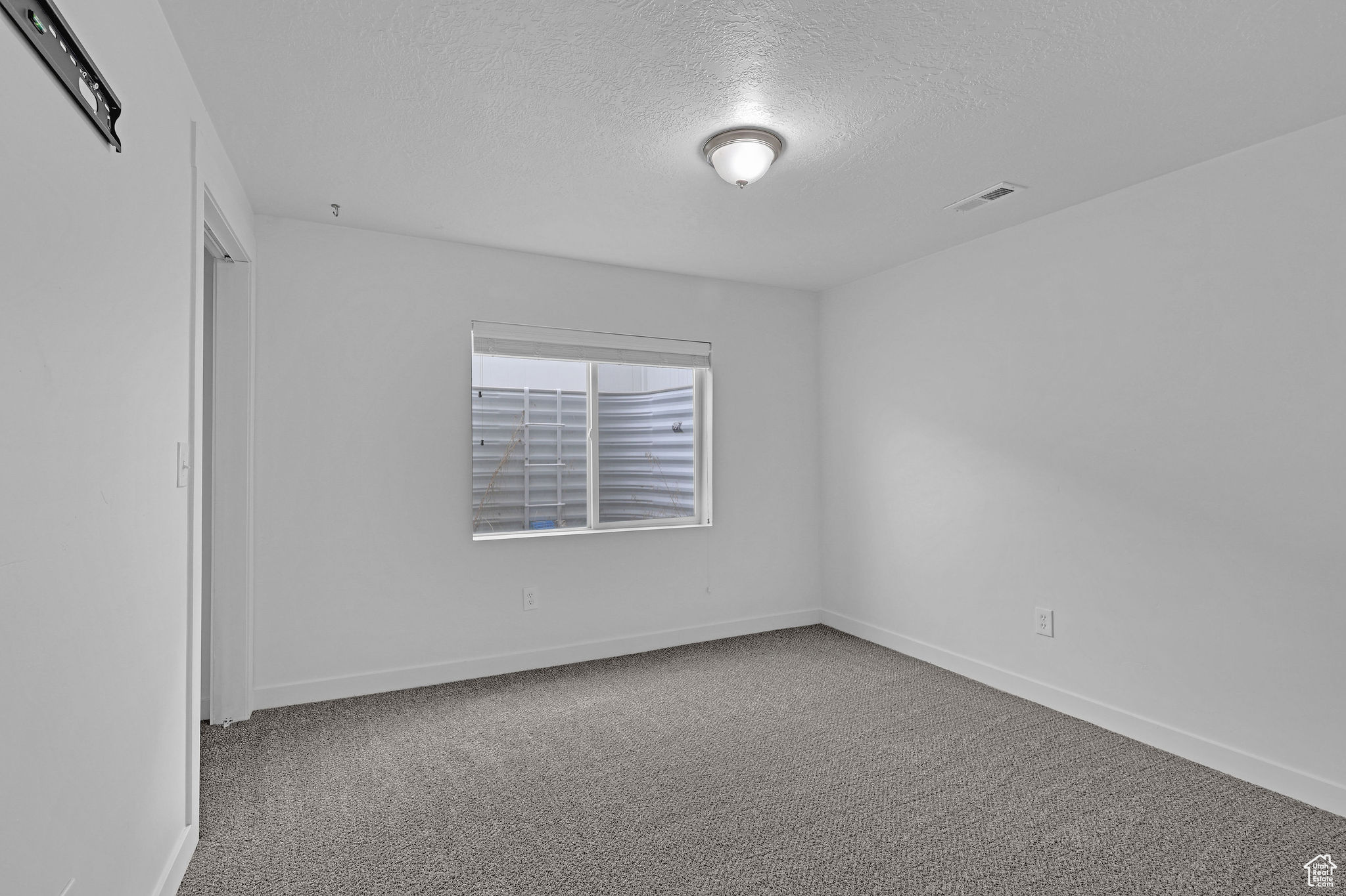 Carpeted spare room with a textured ceiling